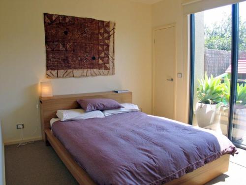 a bedroom with a large bed with a large window at Seaside Idaho in Point Lonsdale