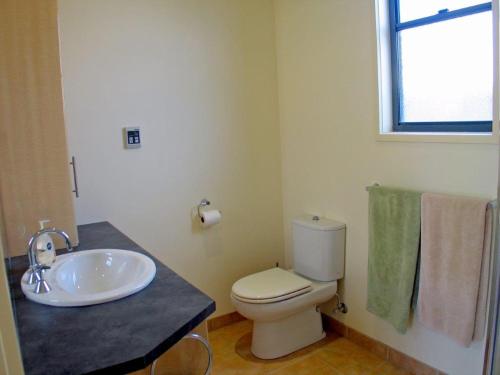a bathroom with a sink and a toilet and a window at Seaside Idaho in Point Lonsdale