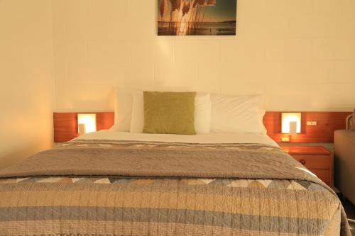 a bed in a bedroom with two lights on at Papakura Motor Lodge & Motel in Papakura