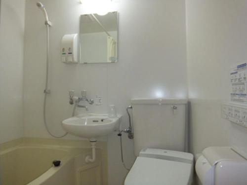 a white bathroom with a toilet and a sink at Hotel Wakasa in Ashikaga