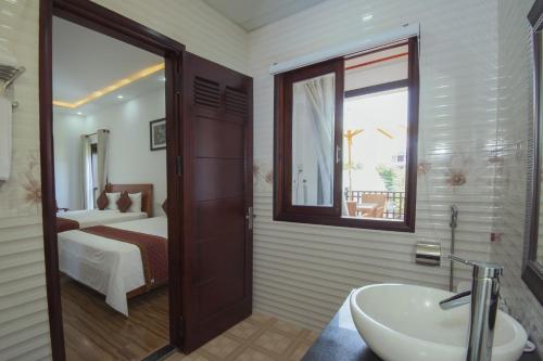 a bathroom with a sink and a bedroom with a bed at Hoi An Sun Lake Villa in Hoi An