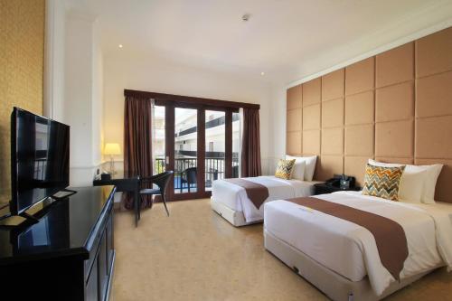 a hotel room with two beds and a flat screen tv at Grand Palace Hotel Sanur - Bali in Sanur