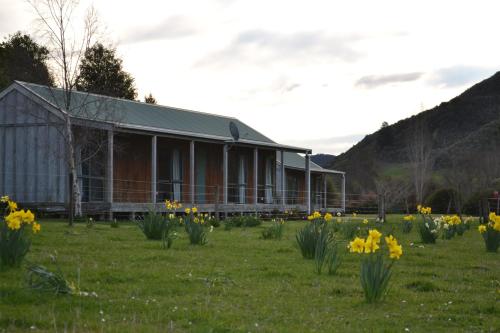 a building with a field of flowers in front of it at Smiths Farm Holiday Park in Linkwater