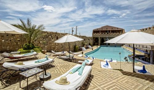 a beach area with chairs, tables and umbrellas at Hotel Kasbah Le Mirage & Spa in Marrakech