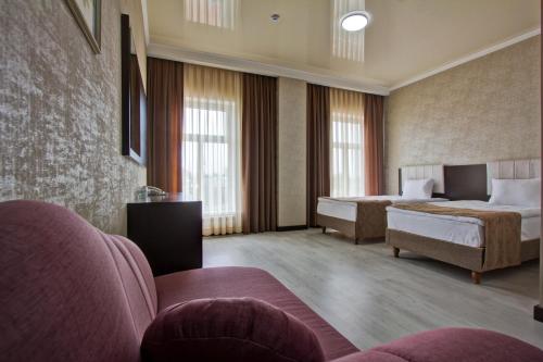 a hotel room with two beds and a couch at Karagat Hotel in Karakol