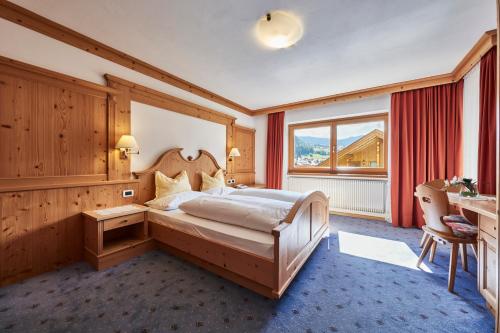 a bedroom with a large bed and a large window at La Cianò in Corvara in Badia