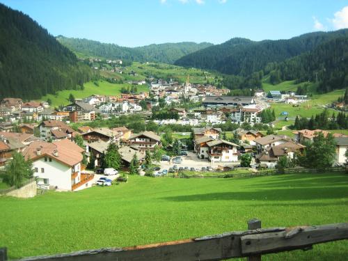 a village on a hill with a green field at La Cianò in Corvara in Badia