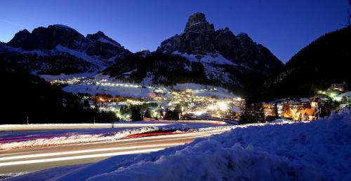 a snowy street with a city and mountains at night at La Cianò in Corvara in Badia