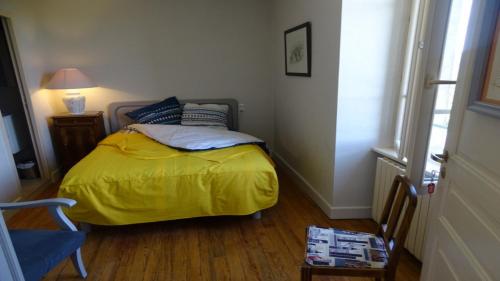 a bedroom with a bed with a yellow blanket and a table at Gite Le Lucimond in Saint-André