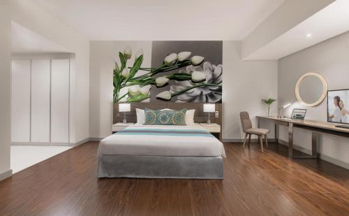 a bedroom with a bed and a desk and a mirror at Citadines Millennium Ortigas Manila in Manila
