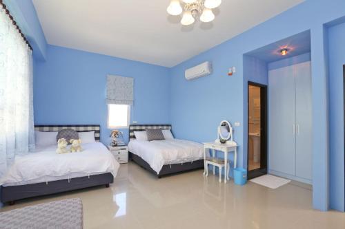 台東市的住宿－臺東假期民宿，一间卧室设有两张床和蓝色的墙壁