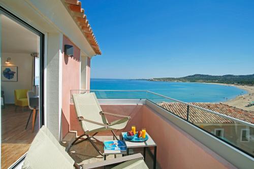 a balcony with a chair and a view of the ocean at Hôtel Serenada in Algajola