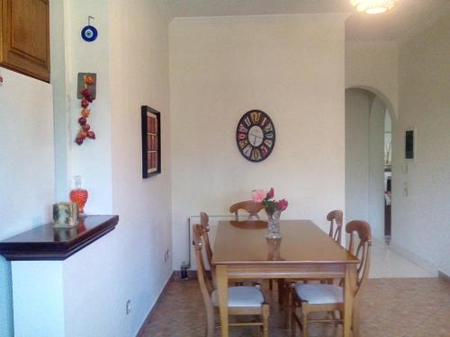 a dining room with a table and a clock on the wall at Villa Rose Garden in Agios Ioannis
