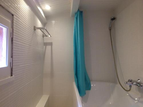 La salle de bains est pourvue d'un rideau de douche bleu et d'une baignoire. dans l'établissement Villa Margaux, à Sillans-la-Cascade