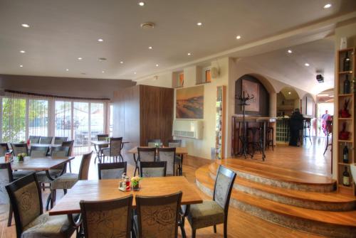 a restaurant with wooden tables and chairs and a staircase at Bokun Apartments II in Sisak