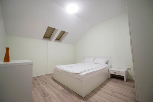 ティミショアラにあるGaga Residence 16の白い小さなベッドルーム(ベッド1台、ナイトスタンド付)