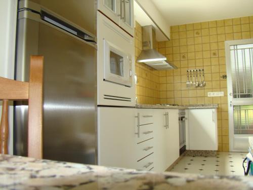 a kitchen with white cabinets and a stainless steel refrigerator at Apartamento Pedras in Vilagarcia de Arousa