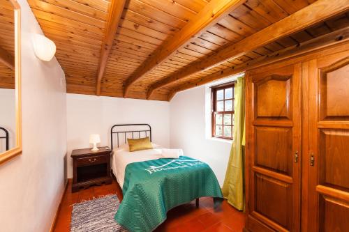 a bedroom with a bed and a wooden ceiling at Adega do Pereirinha in São Roque do Pico