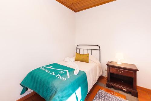 a bedroom with a bed and a table with a bedspread at Adega do Pereirinha in São Roque do Pico