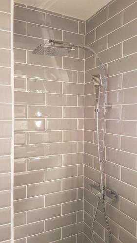 La salle de bains est pourvue d'une douche avec un tuyau et de carrelage blanc. dans l'établissement Super studio cap d'agde, au Cap d'Agde