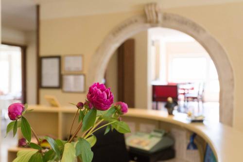 a vase with a pink flower in front of a mirror at Aktiv Hotel Eden in Dro