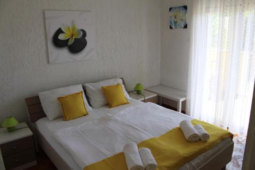 a bedroom with a large white bed with yellow pillows at Apartments Nadia2 in Baška