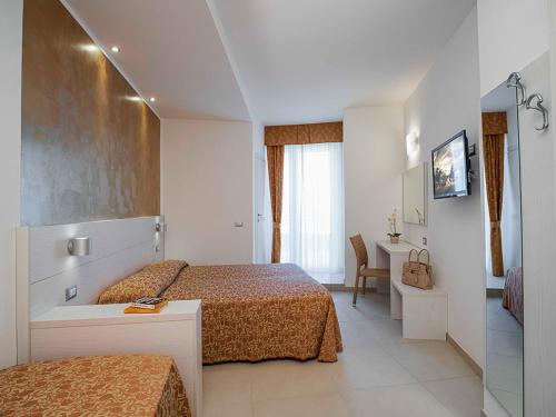 a hotel room with two beds and a desk and a room at Hotel Tibidabo in Bellaria-Igea Marina