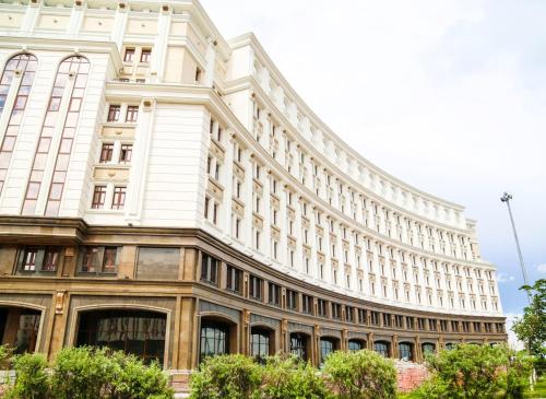 a large white building with trees in front of it at The Arc Residence in Astana