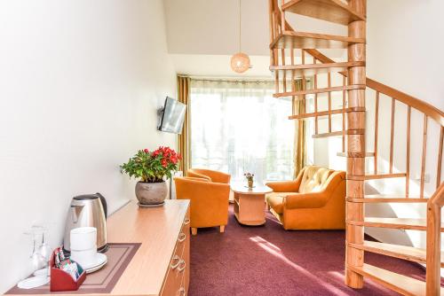 a living room with a spiral staircase and orange chairs at Muza Hotel in Palanga