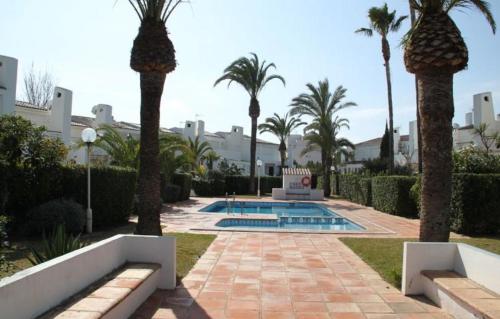 a swimming pool with palm trees in a resort at Urbanisation Les Basetes in Denia