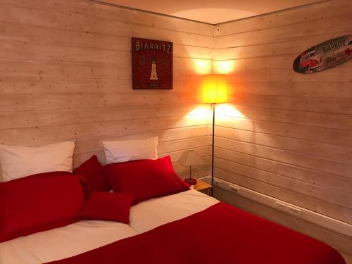 Un dormitorio con una cama con almohadas rojas y una lámpara. en Chez Phil et Dom en Biarritz