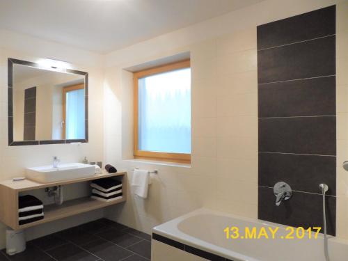 uma casa de banho com um lavatório, uma banheira e um espelho. em Leitnerhof em Terento