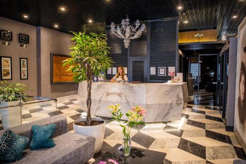 a woman sitting at a counter in a room with plants at Ribas Duke Boutique Hotel in Odesa