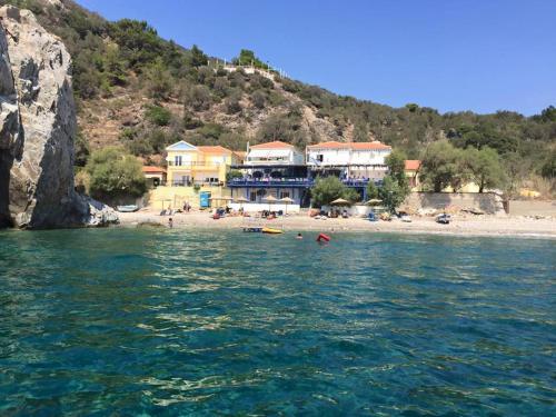 a resort on a beach with people in the water at Psaros Melinta in Plomari