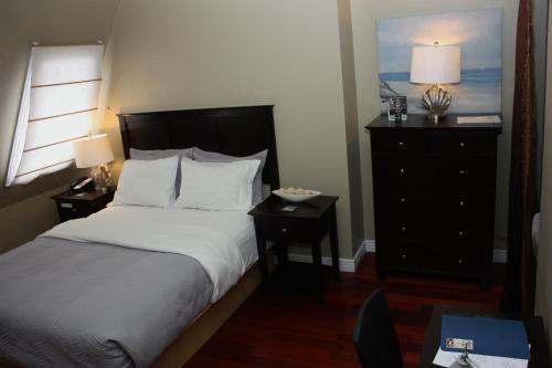 a bedroom with a bed and a dresser with two lamps at The Duckworth Inn in St. John's