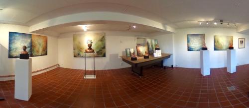 a room with a table and paintings on the walls at Tryde 1303 B&B på Österlen in Tomelilla
