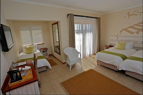 una habitación de hotel con 2 camas y una silla en Stay @ Swakop en Swakopmund