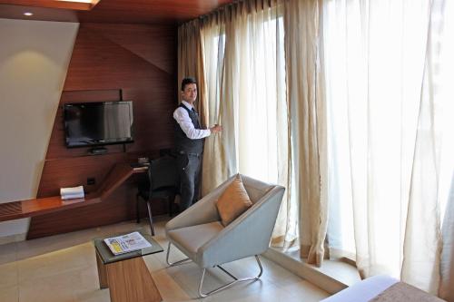 mężczyzna stojący w pokoju hotelowym patrzący przez okno w obiekcie Dragonfly Hotel- The Art Hotel w Bombaju
