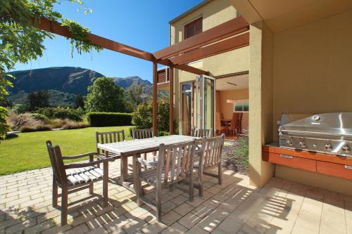 a patio with a table and chairs and a grill at Millbrook Resort in Arrowtown