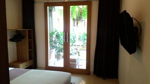 - une chambre avec une porte coulissante en verre donnant sur une terrasse dans l'établissement Kubu Carik, à Legian
