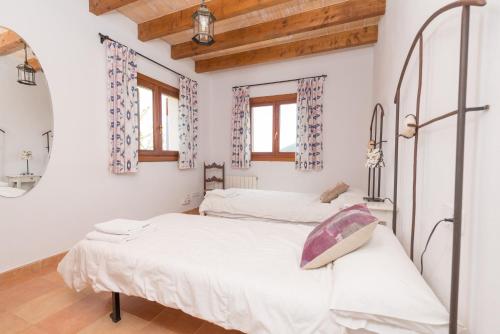 two beds in a room with white walls and wooden ceilings at Vora Pula Golf II in Son Servera