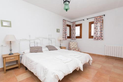 a bedroom with a white bed and a chair at Vora Pula Golf II in Son Servera