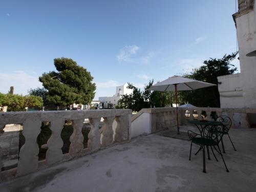 a table and chair with an umbrella on a balcony at Masseria Maccarone in Fasano