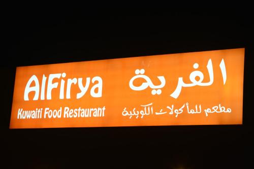 a sign for a food restaurant with arabic writing on it at Aquamarine Kuwait Resort(Families Only) in Al Nuwaiseeb