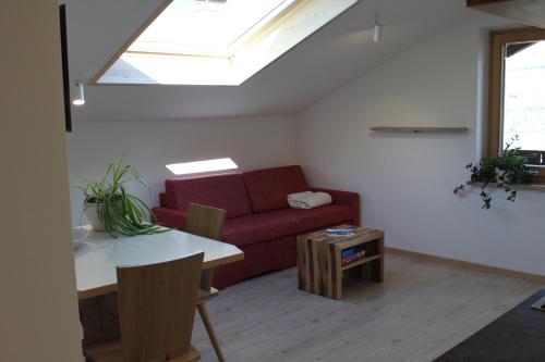 a living room with a red couch and a table at Pension Baumgarten in Naturno