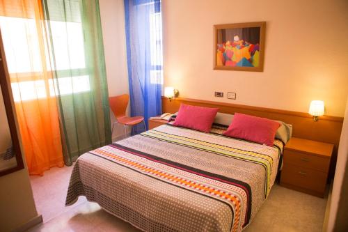 a bedroom with a bed with two red pillows at Hotel Madrid in Santiago de la Ribera