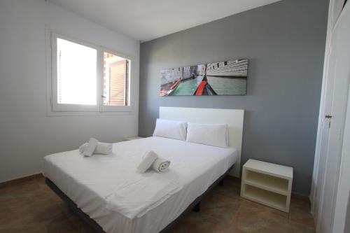 een slaapkamer met een wit bed en een raam bij For a Stay Sant Jordi in Salou