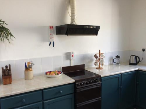 a kitchen with blue cabinets and a bowl of fruit on the counter at Faythe Holiday Home Wexford Town in Wexford
