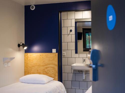 a bedroom with a bed and a sink and a mirror at Eklo Hotels Lille in Lille