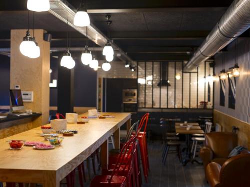 a long table in a restaurant with red chairs at Eklo Hotels Lille in Lille